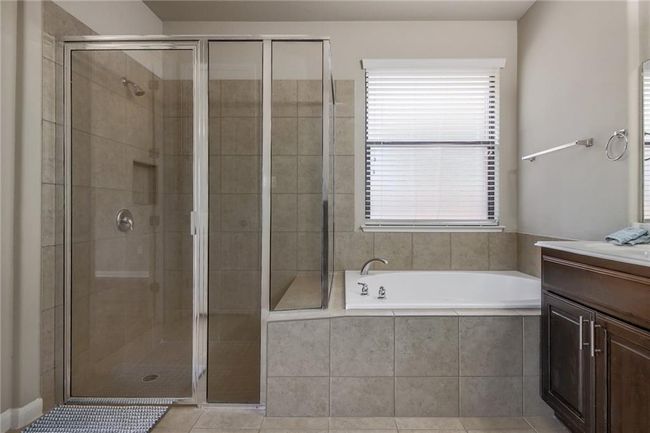 Full bathroom featuring vanity, a bath, a shower stall, and tile patterned flooring | Image 18
