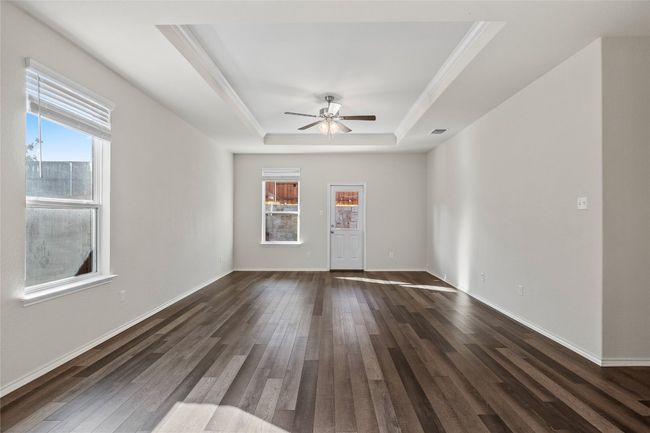 Great room with crown molding, plenty of natural light, a tray ceiling, and laminate / wood-style flooring | Image 19