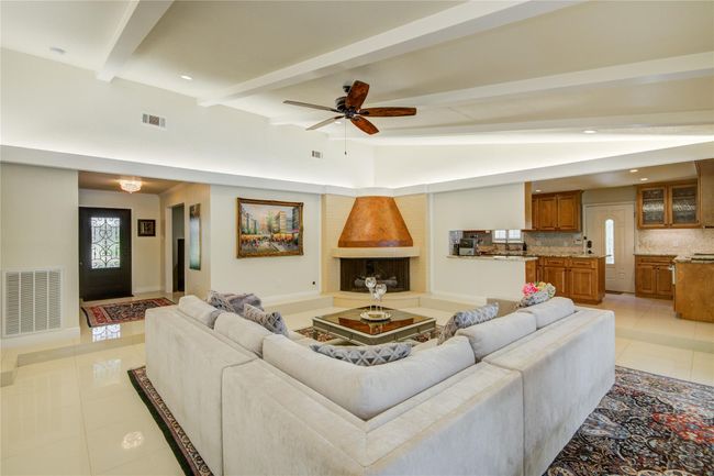 The open-concept layout seamlessly connects the dining area to this inviting family room, anchored by a distinctive fireplace and surrounded by comfortable seating. | Image 7