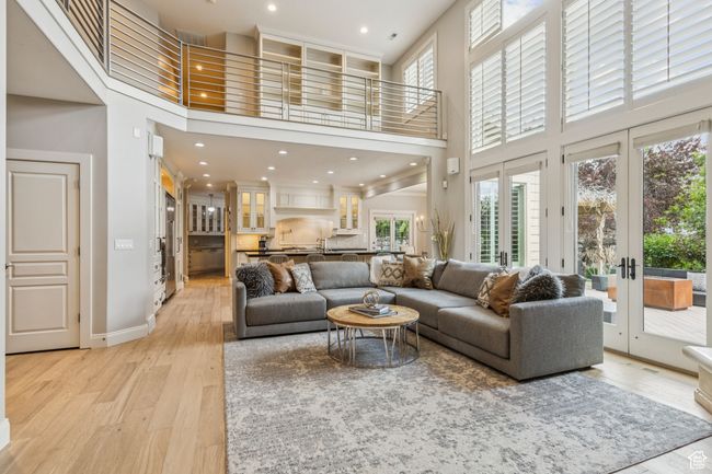 Living area with a towering ceiling, french doors, healthy amount of natural light, light wood-style floors, and recessed lighting | Image 13