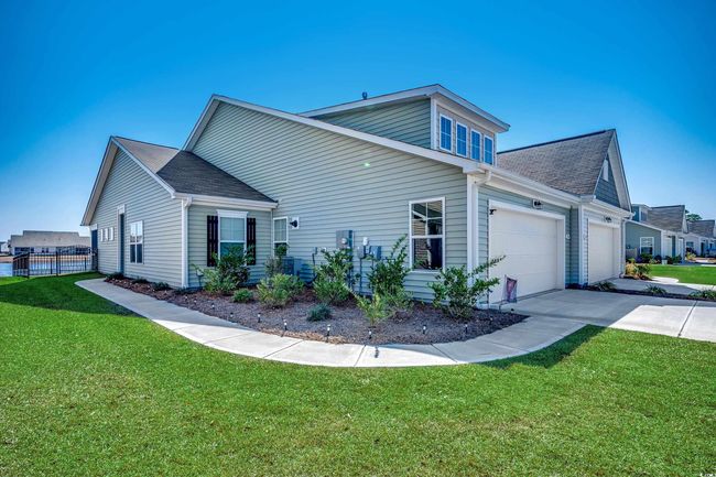 View of side of property featuring a yard, concrete driveway, roof with shingles, and an attached garage | Image 4
