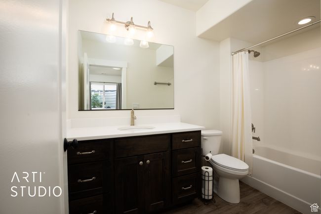 Full bathroom with wood-type flooring, toilet, shower / bath combo with shower curtain, and vanity | Image 39