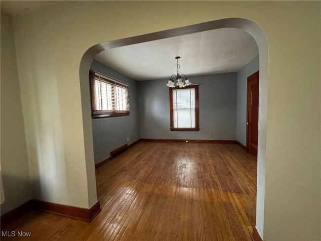 Empty room with arched walkways, hardwood / wood-style floors, and baseboards | Image 12