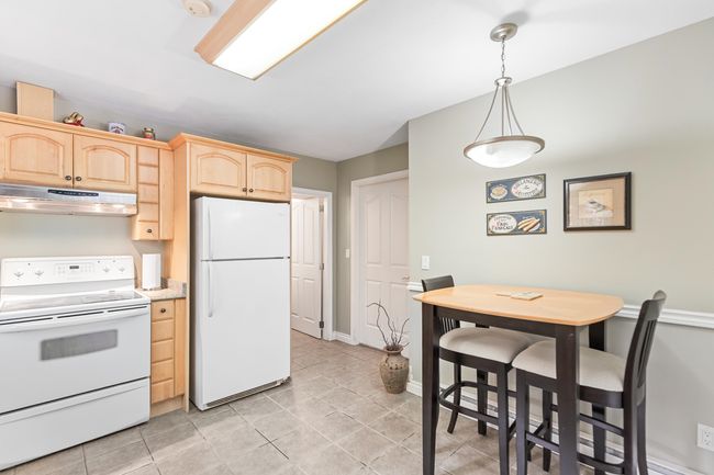 Kitchen featuring white appliances, under cabinet range hood, light brown cabinets, light tile patterned flooring, and pendant lighting | Image 33