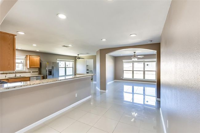 Kitchen featuring ceiling fan, appliances with stainless steel finishes, arched walkways, brown cabinets, and recessed lighting | Image 9