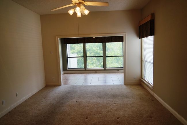 Carpeted empty room with plenty of natural light, a ceiling fan, baseboards, tile patterned floors, and a textured ceiling | Image 16