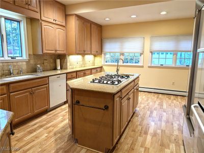 Kitchen featuring stainless steel gas cooktop, a baseboard heating unit, white dishwasher, and a wealth of natural light | Image 3