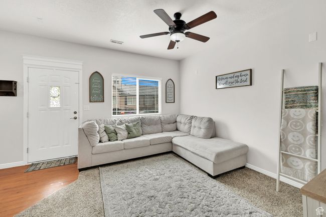 Living area with wood finished floors, a ceiling fan, visible vents, baseboards, and a textured ceiling | Image 10