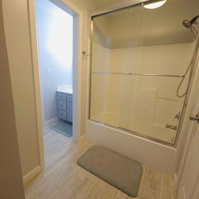 Full bath featuring shower / bath combination with glass door, wood finished floors, and vanity | Image 22