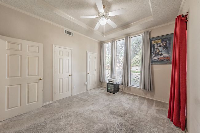 Unfurnished bedroom featuring a textured ceiling, a raised ceiling, ornamental molding, carpet floors, and ceiling fan | Image 16