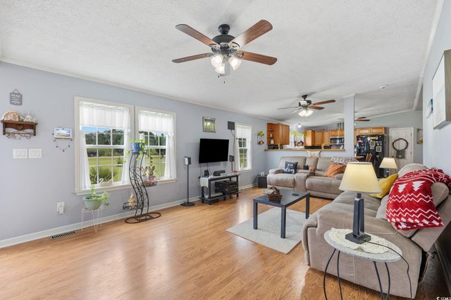 Kitchen with black appliances, ceiling fan, backsplash, a breakfast bar area, and ornamental molding | Image 12