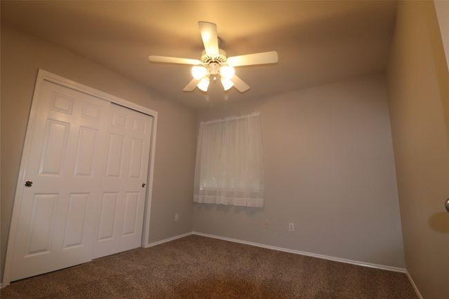 Unfurnished bedroom featuring dark carpet, a closet, and a ceiling fan | Image 14