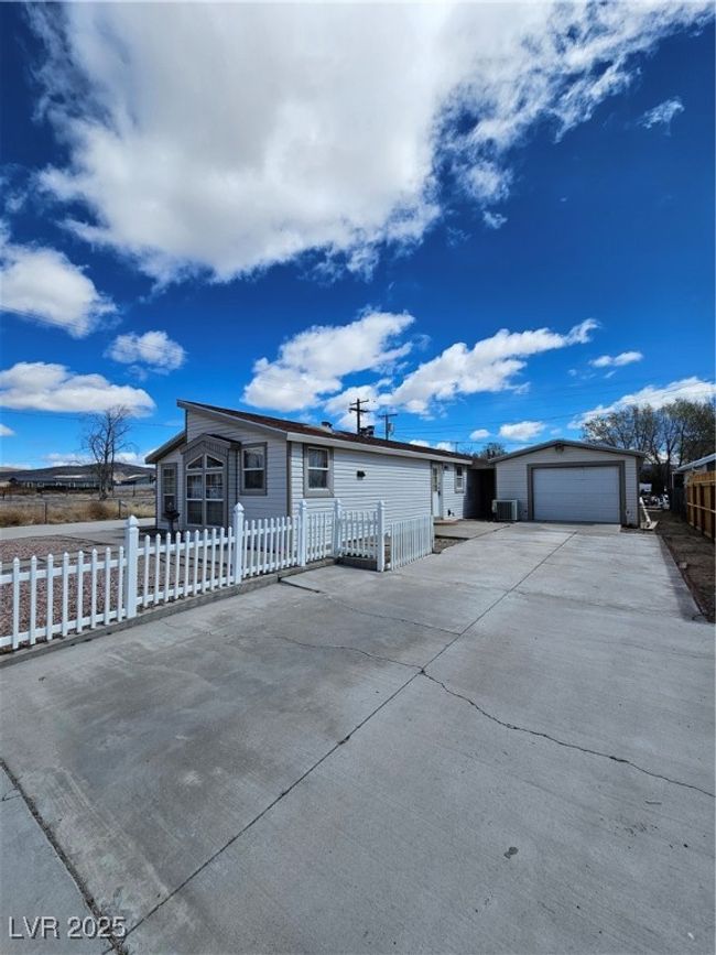 Manufactured / mobile home featuring driveway, a fenced front yard, an outbuilding, and an attached garage | Image 6