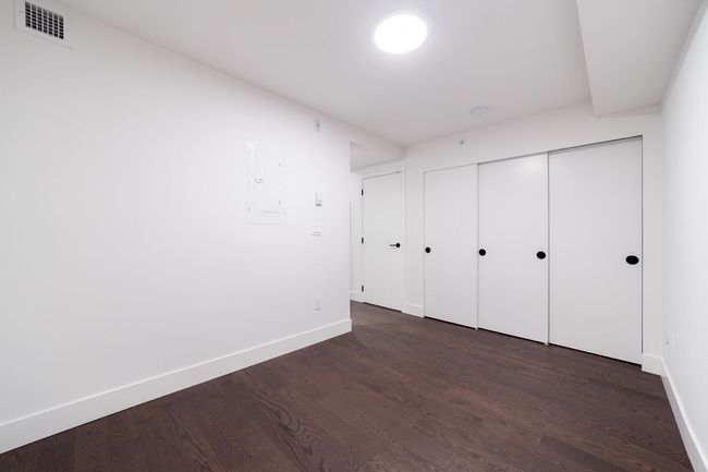 Unfurnished bedroom with electric panel, dark wood-style flooring, and a closet | Image 27
