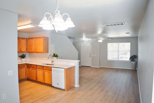 Kitchen with white dishwasher, a chandelier, a peninsula, light wood-style floors, and light countertops | Image 12