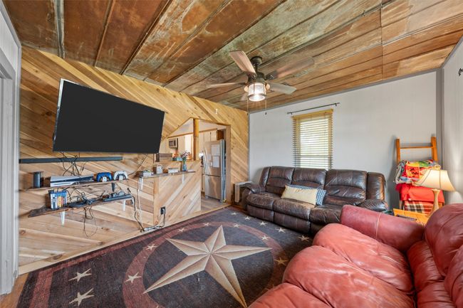 Living area featuring a ceiling fan, wood ceiling, and wood walls | Image 4