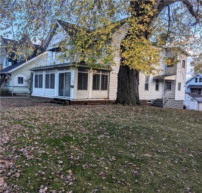 Rear view of property featuring a lawn and a sunroom | Image 1