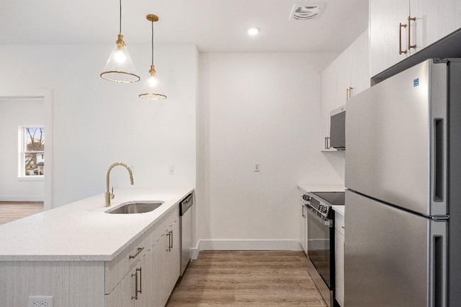 Kitchen featuring stainless steel appliances, a sink, a peninsula, light wood-style flooring, and white cabinets | Image 8