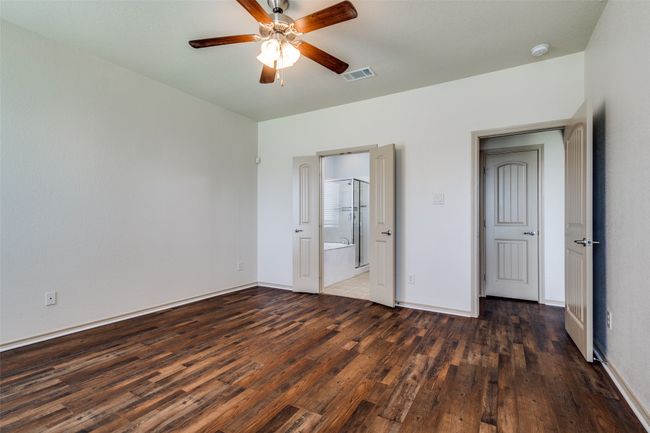 Unfurnished bedroom with wood finished floors, ensuite bathroom, and ceiling fan | Image 20