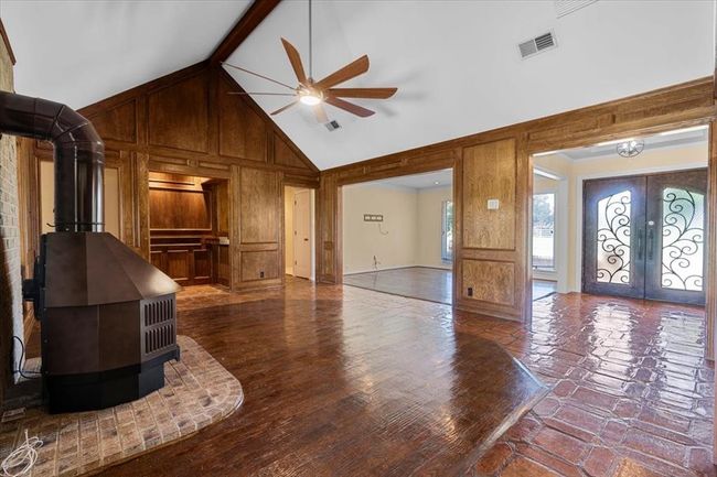 Unfurnished living room with wood walls, wood-type flooring, french doors, and ceiling fan | Image 3