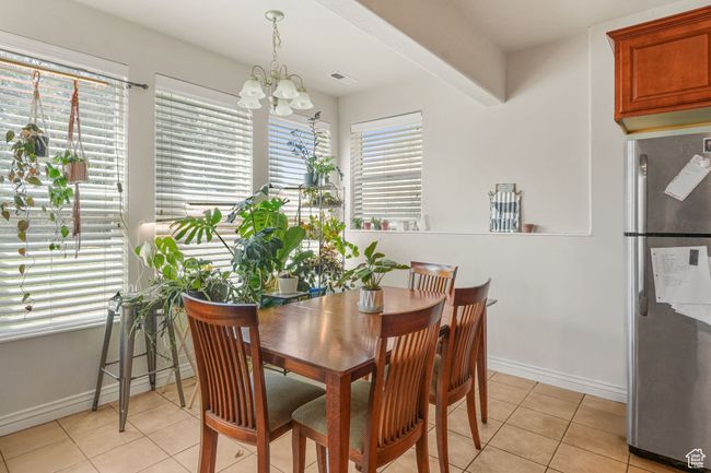 Dining room featuring light tile patterned floors, visible vents, a notable chandelier, and baseboards | Image 19