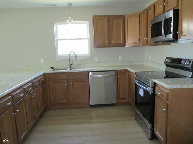 kitchen featuring a sink, light wood-type flooring, brown cabinets, and stainless steel appliances | Image 6