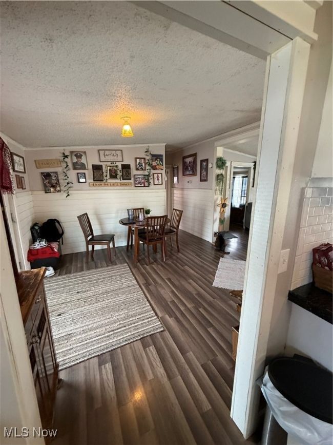 Dining area featuring wainscoting, a textured ceiling, and dark wood finished floors | Image 15