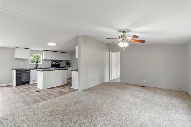 Kitchen with a center island, a sink, dark countertops, white cabinetry, and dishwasher | Image 22
