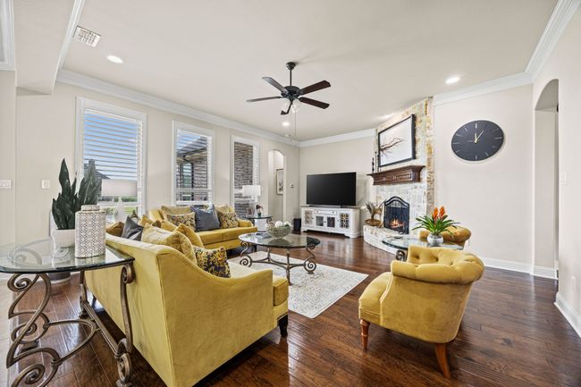 Living area with arched walkways, a ceiling fan, a fireplace, wood flooring, and recessed lighting | Image 5