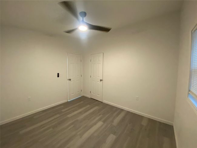 Empty room with ceiling fan, dark wood-style flooring, and baseboards | Image 15