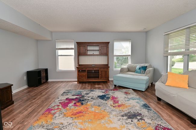 living room with wood finished floors, a textured ceiling, and baseboards | Image 5