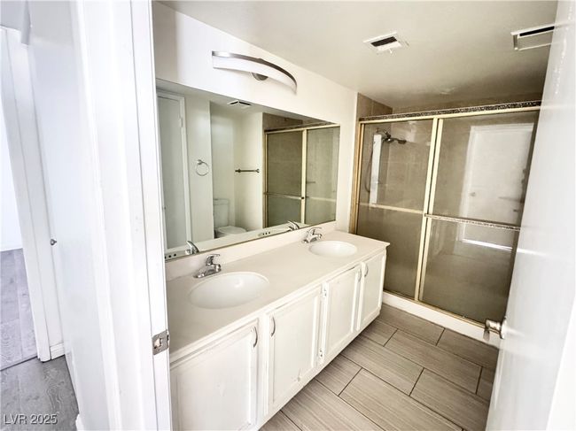 Bathroom featuring double vanity, a shower stall, and wood finish floors | Image 12