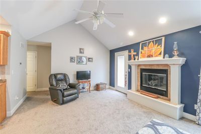 Living room featuring carpet, vaulted ceiling, ceiling fan and electric fireplace | Image 2