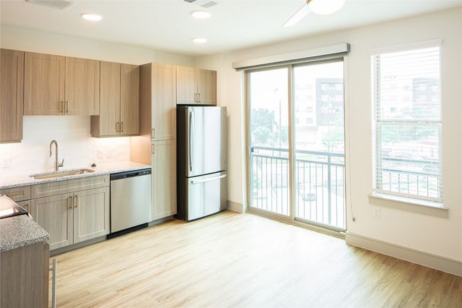 Kitchen featuring appliances with stainless steel finishes, a sink, light stone countertops, and light wood-style floors | Image 14