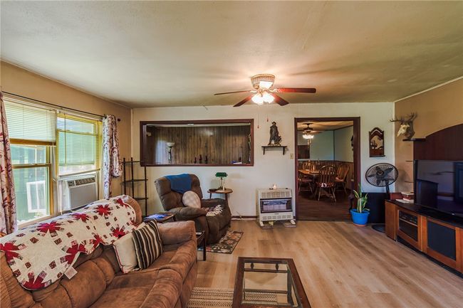 Living room featuring heating unit, wood finished floors, ceiling fan, and cooling unit | Image 15