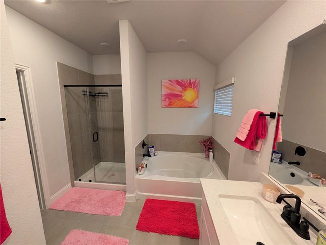 Bathroom featuring a bath, a stall shower, vanity, and lofted ceiling | Image 5