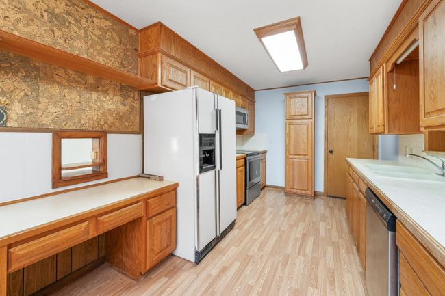 Kitchen with appliances with stainless steel finishes, light wood-style flooring, light countertops, and an office area | Image 15