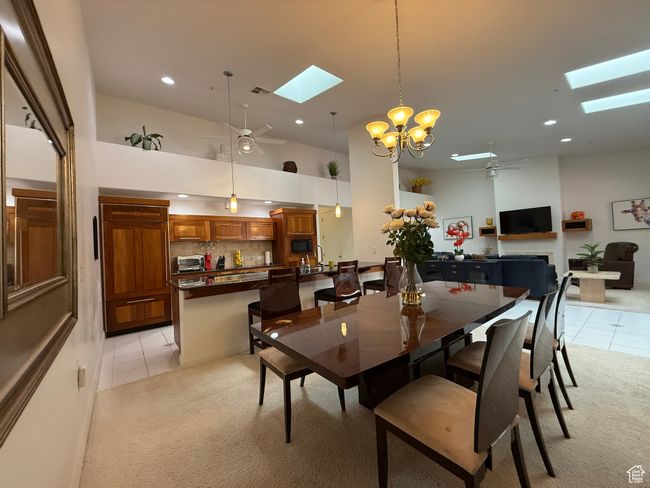 Dining area with a skylight, light tile patterned flooring, and ceiling fan with notable chandelier | Image 4
