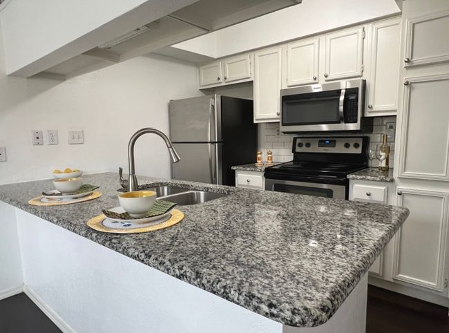 Kitchen featuring decorative backsplash, a sink, dark stone countertops, and appliances with stainless steel finishes | Image 5