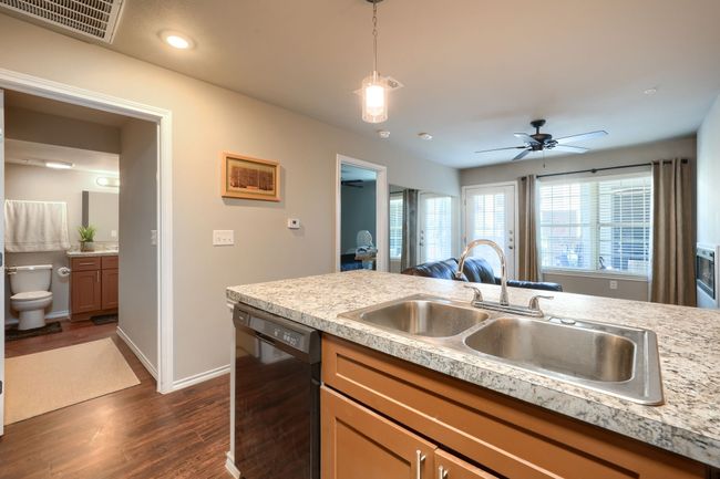 Kitchen featuring visible vents, dark wood-style flooring, a sink, light countertops, and black dishwasher | Image 11
