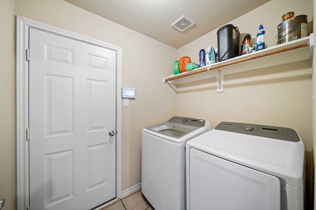 Laundry room featuring a textured ceiling, visible vents, laundry area, washing machine and dryer, and light tile patterned floors | Image 35