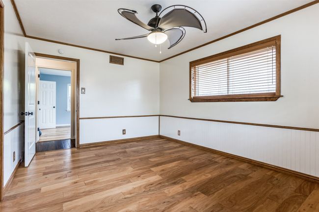 Spare room featuring light wood-style flooring, ceiling fan, crown molding, a wainscoted wall, and baseboards | Image 29