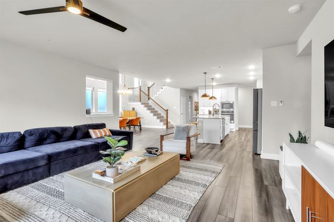 Living room featuring ceiling fan, baseboards, wood finished floors, and stairs | Image 10
