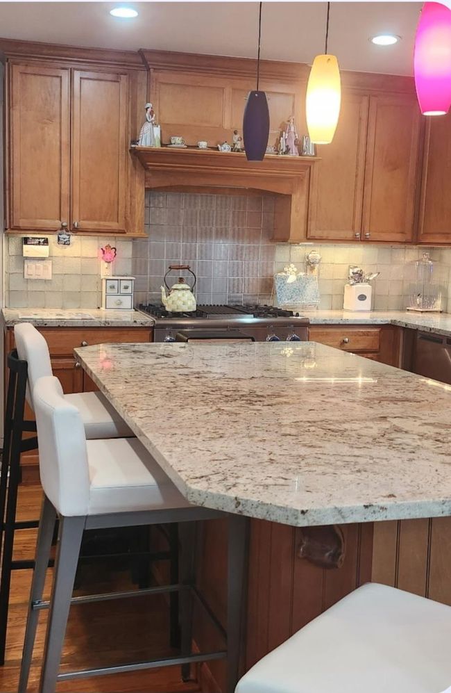 Kitchen with brown cabinets, decorative backsplash, light stone counters, and range | Image 16