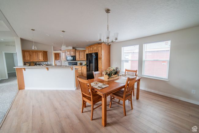Dining room with vaulted ceiling, an inviting chandelier, light wood-style floors, and baseboards | Image 26