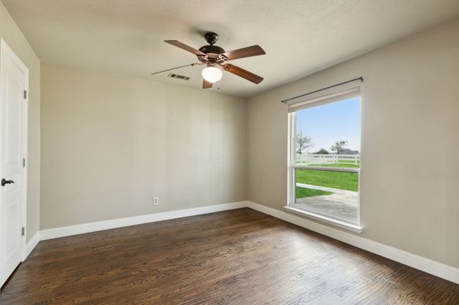 Unfurnished room featuring a ceiling fan, dark wood-style floors, visible vents, and baseboards | Image 5