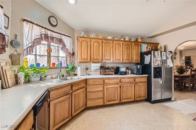 Kitchen featuring lofted ceiling, light countertops, a sink, stainless steel fridge, and dishwashing machine | Image 13