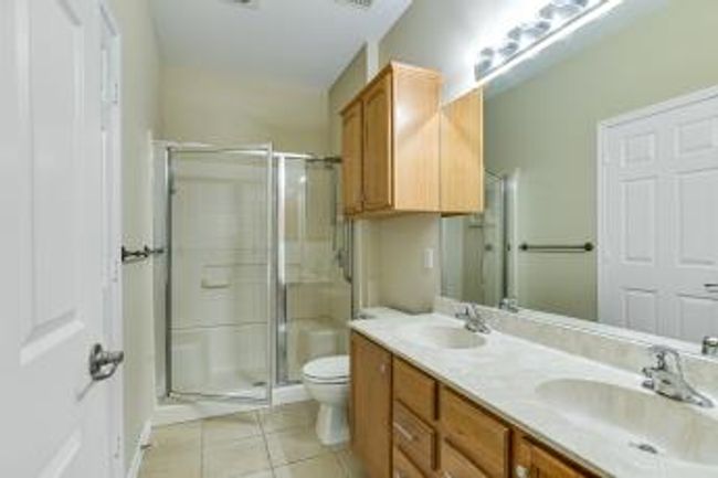 Full bathroom featuring double vanity, tile patterned floors, and a stall shower | Image 7