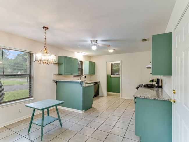 Kitchen with green cabinetry, range with gas stovetop, light tile patterned floors, and dishwasher | Image 14