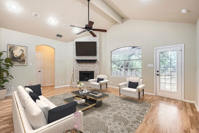 Living room with healthy amount of natural light, a ceiling fan, arched walkways, and a brick wood burning fireplace | Image 4